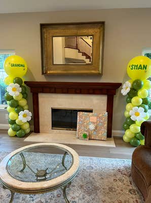 A living room with the fire place surrounded by decorative daisy balloon stands with "Grandma" on on side.