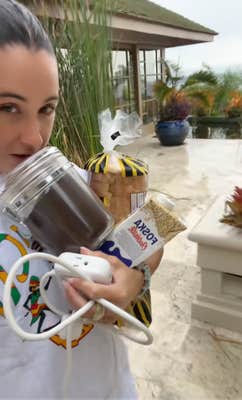 A woman carrying food, coffee grounds, and extension cords to the hurricane shelter.