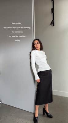 A woman posing in a white top and black skirt, her "betrayal list" on the screen.