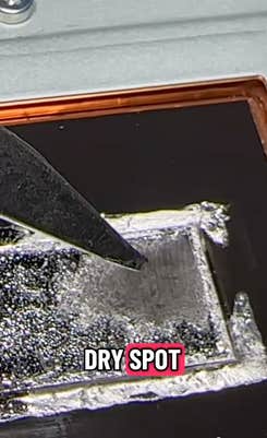 A metal rod pointing at a dry spot on the inside of a PS5.