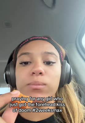 Woman staring at her camera eating a chicken nugget, unamused. Text overlay reads, "praying for any girl who just got the forehead kiss of doom #2weeksmax"