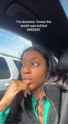 Imani recording in the car. She has one hand to her chin in thought. Text overlay reads, "I'm shocked. I knew the world was evil bu SHEESH."