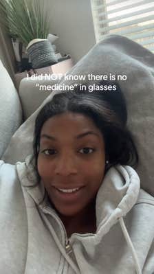 A young Black woman lying back on her couch and talking to the camera.