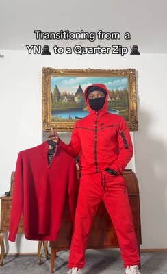 Black man in all red Nike Tech outfit holding up a crew neck sweater to one side.