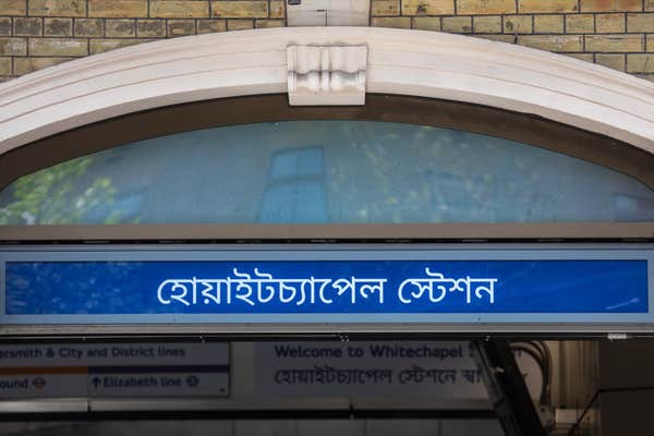 Close-up of the entrance to Whitechapel station, written in the Bengali language, in London, UK.
