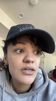 Marissa Bode in a baseball cap and grey sweater staring off-camera as she talks.