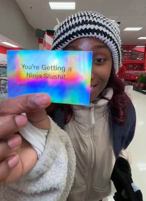 TikTok video of a woman in Target showing a card to the camera that says "You're Getting a Ninja Slushi!"